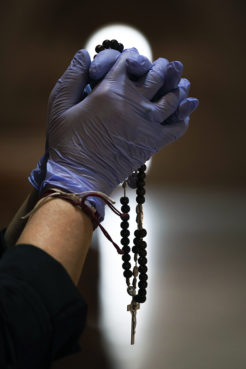 A Catholic worshipper using protective gloves prays with a rosary at the Santa Maria de Cana parish in Pozuelo de Alarcon, outskirts Madrid, Spain, Sunday, March 15, 2020. (AP Photo/Bernat Armangue)