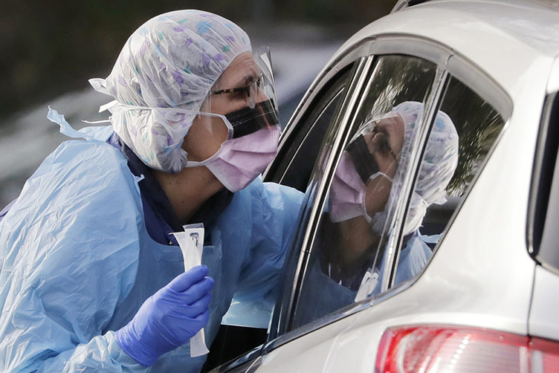 Laurie Kuypers, a registered nurse, reaches into a car to take a nasopharyngeal swab from a patient at a drive-through COVID-19 coronavirus testing station for University of Washington Medicine patients, on March 17, 2020, in Seattle. (AP Photo/Elaine Thompson)