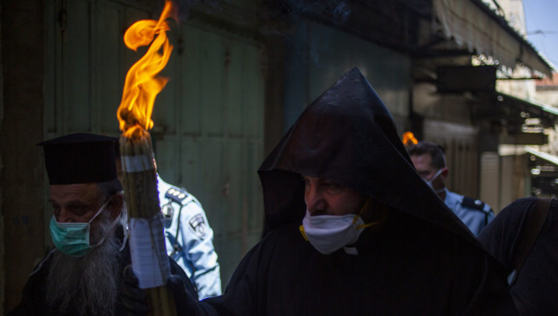 An Orthodox clergyman holds holy fire  to transfer to predominantly Orthodox countries from the Church of the Holy Sepulchre, traditionally believed by many Christians to be the site of the crucifixion and burial of Jesus Christ, in Jerusalem's old city after the traditional Holy Fire ceremony was called off amid coronavirus, Saturday, April 18, 2020. A few clergymen on Saturday marked the Holy Fire ceremony as the coronavirus pandemic prevented thousands of Orthodox Christians from participating in one of their most ancient and mysterious rituals at the Jerusalem church marking the site of Jesus' tomb.(AP Photo/Ariel Schalit)