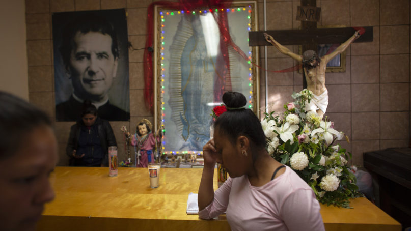 In this Feb. 26, 2019 photo, a woman waits beside an altar at the San Juan Bosco migrant shelter, in Nogales, Mexico. Presently, the shelter is housing about 150 migrants from Central America and Mexico, many of the who are seeking asylum in the United States because they claim they are fleeing gang -related violence in their home countries. (AP Photo/Dario Lopez-Mills)