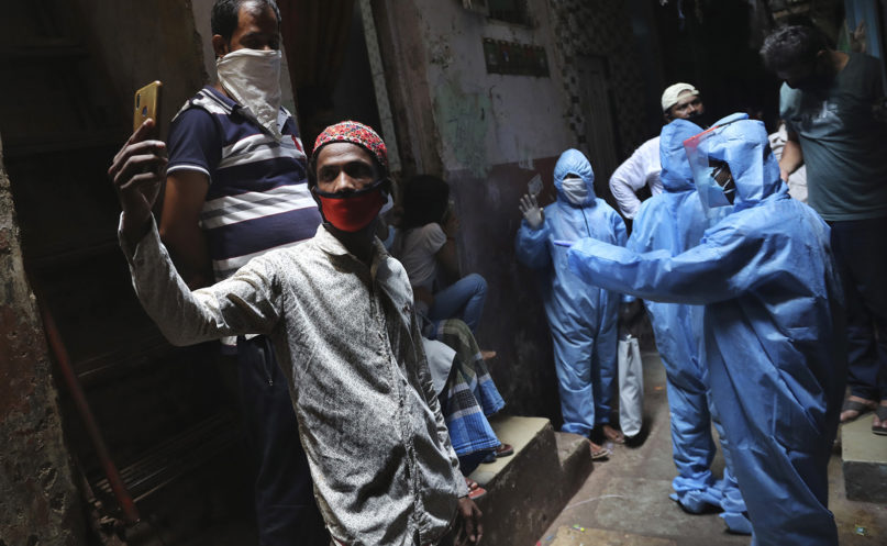 A man wearing mask takes selfie as health workers collect details of residents in Dharavi, one of Asia's largest slums, during lockdown to prevent the spread of the new coronavirus in Mumbai, India, Monday, April 13, 2020. (AP Photo/Rafiq Maqbool)