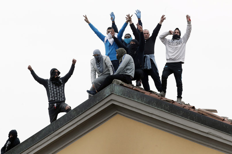 Inmates stage a protest against new rules to cope with the coronavirus emergency, including the suspension of relatives' visits, on the roof of the San Vittore prison in Milan, Italy, Monday, March 9, 2020. (AP Photo/Antonio Calanni)
