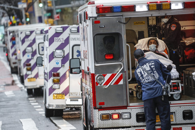 A patient arrives in an ambulance, cared for by medical workers wearing personal protective equipment due to COVID-19 concerns, outside NYU Langone Medical Center, Monday, April 13, 2020, in New York. (AP Photo/John Minchillo)