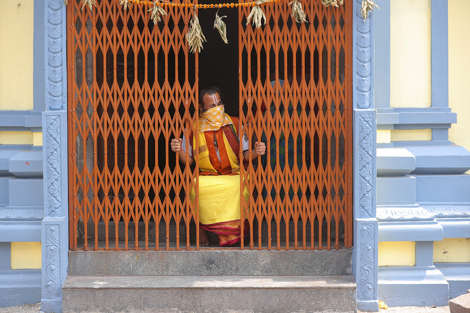 A Hindu priest looks out from a temple during lockdown to prevent the spread of new coronavirus in Hyderabad, India, Tuesday, April 14, 2020. Indian Prime Minister Narendra Modi on Tuesday extended the world's largest coronavirus lockdown to head off the epidemic's peak, with officials racing to make up for lost time. (AP Photo/Mahesh Kumar A.)