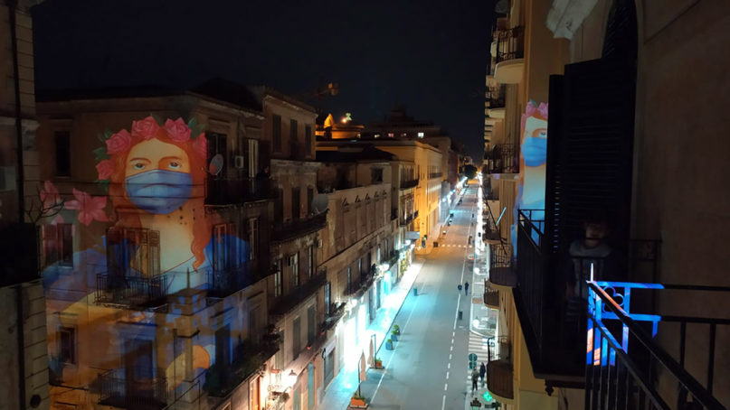 Images of St. Rosalia, wearing a face mask, are projected onto buildings in Palermo, Sicily, in southern Italy. Photo courtesy of Ex Voto Collective Palermo