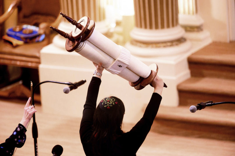 In this Feb. 1, 2020, photo, Rabbi Jacqueline Mates-Muchin holds a Torah scroll aloft during Shabbat morning service at Temple Sinai in Oakland, California. (AP Photo/Noah Berger)