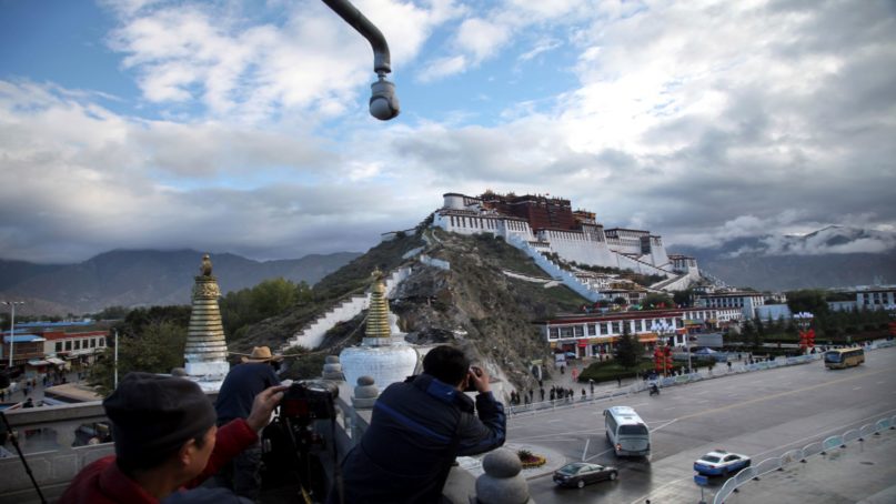 In this Sept. 19, 2015, file photo, tourists take photos of the Potala Palace beneath a security camera in Lhasa, capital of the Tibet Autonomous Region of China. China said May 19, 2020, that a boy who disappeared 25 years ago after being picked by the Dalai Lama as Tibetan Buddhism's second-highest figure is now a college graduate with a stable job. (AP Photo/Aritz Parra, File)