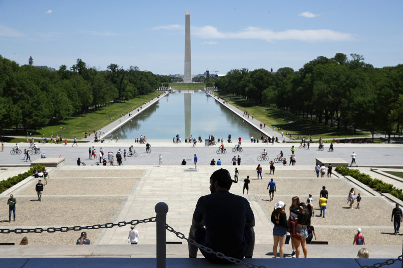 A man sits on the top step of the Lincoln Memorial as people gather by the Lincoln Memorial Reflecting Pool in Washington, Saturday, May 2, 2020. (AP Photo/Patrick Semansky)