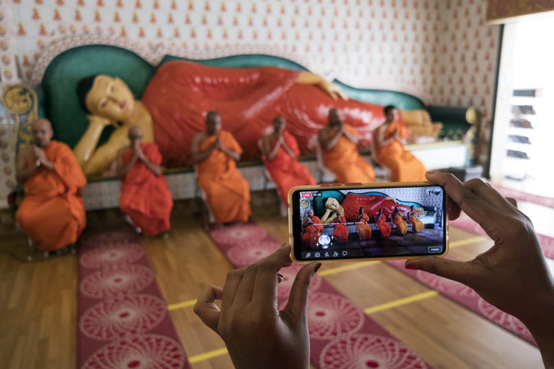Buddhist monks praying on Vesak Day are streamed on social media by a volunteer at the Buddhist Maha Vihara temple in Kuala Lumpur on May 7, 2020. RNS photo by Alexandra Radu