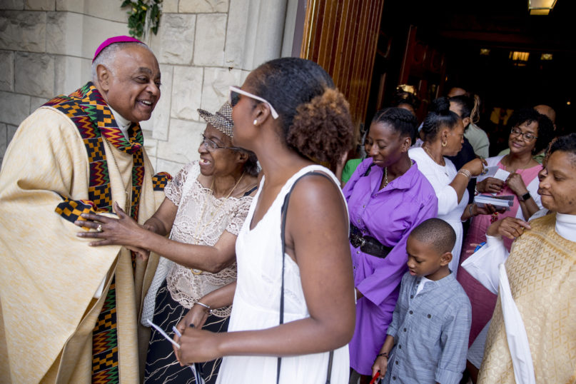 FILE - In this Sunday, June 2, 2019 file photo, Archbishop of Washington Wilton Gregory, left, greets parishioners following Mass at St. Augustine Church in Washington. (AP Photo/Andrew Harnik)