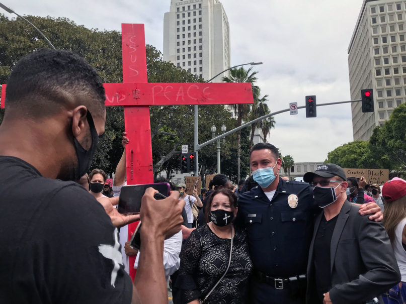 Demonstrators take photos with a police officer outside of the Los Angeles Police Department on June 2, 2020, in Los Angeles. RNS photo by Alejandra Molina