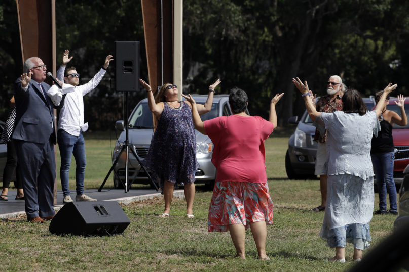 Pastor Bill Bailey, left, prays with some of his congregation during outdoor Easter services, Sunday, April 12, 2020, at the Happy Gospel Center Church in Bradenton, Florida. (AP Photo/Chris O'Meara)