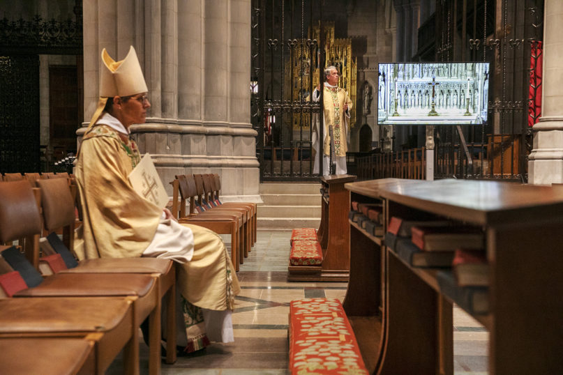 The Rt. Rev. Mariann Edgar Budde, left, bishop of the Episcopal Diocese of Washington, and the Very Rev. Randolph Marshall Hollerith, dean of Washington National Cathedral, right, await their signal to begin a livestreamed Easter Sunday service at the National Cathedral with no parishioners on April 12, 2020, in Washington, in light of coronavirus pandemic precautions. (AP Photo/Jacquelyn Martin)
