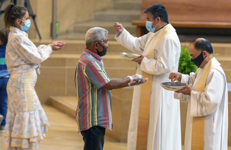 Faithful wear masks and some wear gloves as they receive Communion at the Cathedral of Our Lady of the Angels in downtown Los Angeles, June 7, 2020. (AP Photo/Damian Dovarganes)
