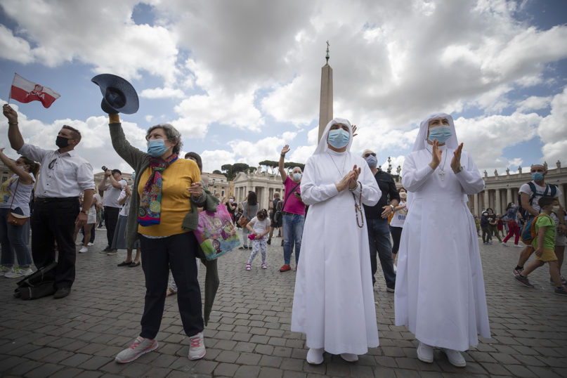 Faithful wearing masks to prevent the spread of COVID-19 wave as Pope Francis delivers his blessing from the window of his studio overlooking St. Peter's Square, at the Vatican, Sunday, June 14, 2020. (AP Photo/Alessandra Tarantino)