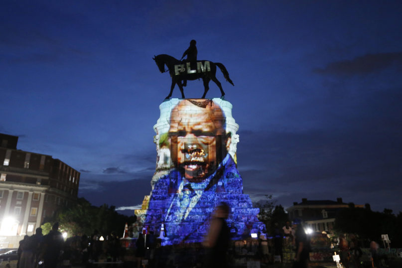 An 2020 image of the late Georgia congressman and civil rights pioneer U.S. Rep. John Lewis is projected onto the pedestal of the statue of confederate Gen. Robert E. Lee, in Richmond, Virginia. The statue was removed in 2021. (AP Photo/Steve Helber)