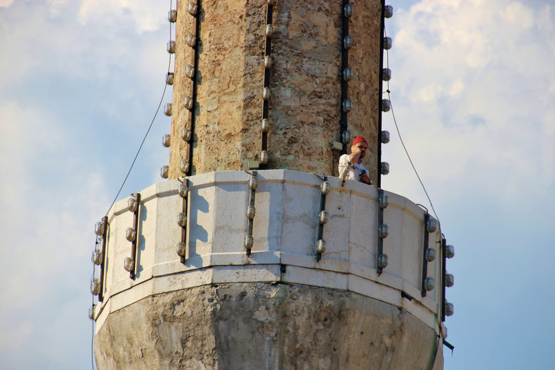 A muezzin calling Muslims to prayer stands on the minaret of the Gazi Husrev-beg mosque in Sarajevo. (Shutterstock)