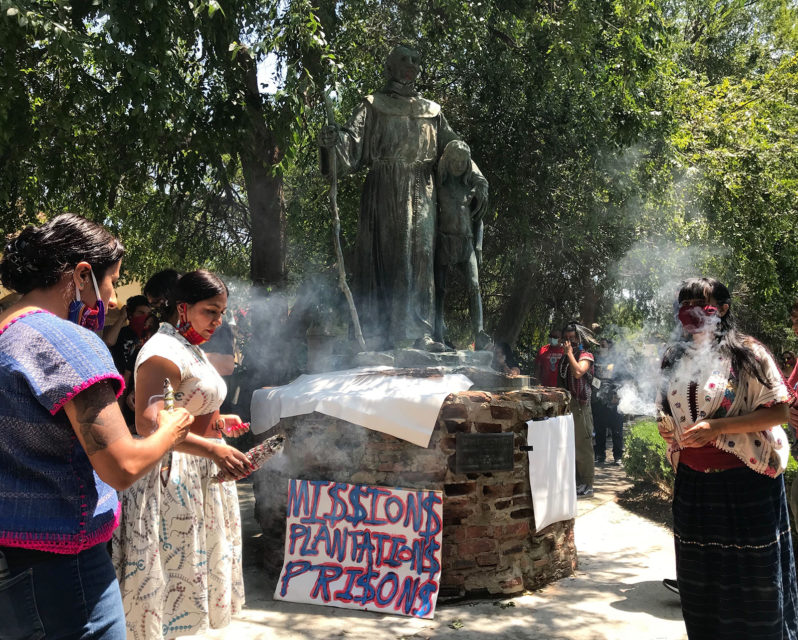 Women burn sage during a ceremony next to the Junipero Serra statue at Brand Park in Mission Hills, California, June 27, 2020. The park is across from the San Fernando Mission. RNS photo by Alejandra Molina