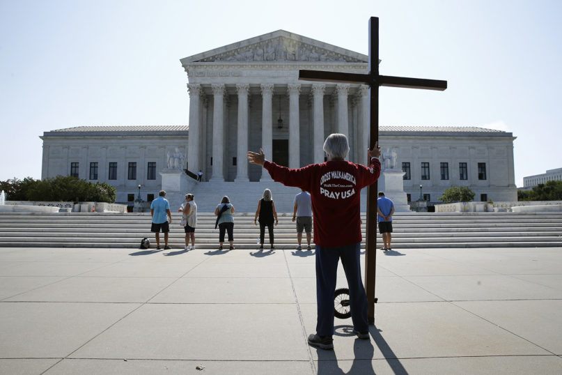 Tom Alexander holds a cross as he prays prior to rulings outside the Supreme Court on Capitol Hill in Washington on July 8, 2020. (AP Photo/Patrick Semansky)