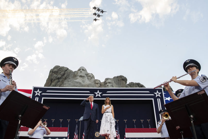 President Donald Trump, accompanied by First Lady Melania Trump, stands during the national anthem with a flyover by the U.S. Navy Blue Angles at Mount Rushmore National Memorial, Friday, July 3, 2020, near Keystone, South Dakota. (AP Photo/Alex Brandon)