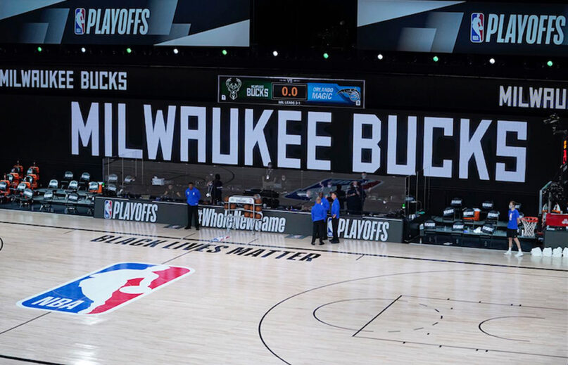 Officials stand beside an empty court at the scheduled start between the Milwaukee Bucks and the Orlando Magic on Wednesday, Aug. 26, 2020, in Orlando. The Bucks didn’t take the floor in protest against racial injustice and the shooting of Jacob Blake. (AP Photo/Ashley Landis)