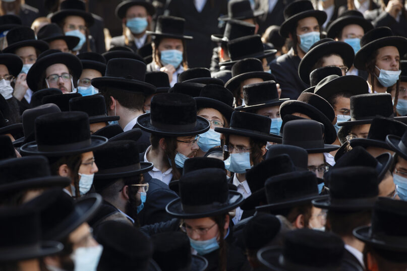 Ultra-Orthodox Jews, followers of the Hasidic sect of Shomrei Emunim, wearing protective face masks to combat the coronavirus outbreak, attend the funeral of Rabbi Refael Aharon Roth, 72, who died from the virus, in Bnei Brak, Israel, on Aug. 13, 2020. (AP Photo/Oded Balilty)