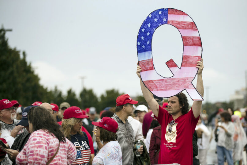 In this Aug. 2, 2018, file photo, David Reinert holds a Q sign while waiting in line with others to enter a campaign rally with President Donald Trump in Wilkes-Barre, Pennsylvania. The far-right QAnon conspiracy theory forged in a dark corner of the internet has come into the mainstream political arena. (AP Photo/Matt Rourke)