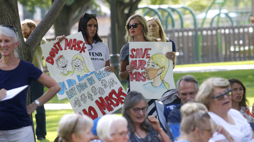 Stephanie Grant, left, and Tiffany Barker join others during an anti-mask rally Wednesday, Aug. 5, 2020, in Orem, Utah. (AP Photo/Rick Bowmer)