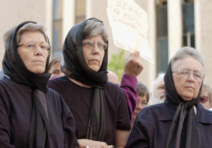 In this July 25, 2003, file photo, Dominican nuns, from left, Ardeth Platte, Carol Gilbert and Jackie Hudson listen to speakers before addressing a crowd outside the federal courthouse in downtown Denver. The women were convicted in April 2003 of obstructing the national defense and damaging government property for swinging a hammer at the silo and smearing their blood on it in the form of a cross. (AP Photo/David Zalubowski, File)
