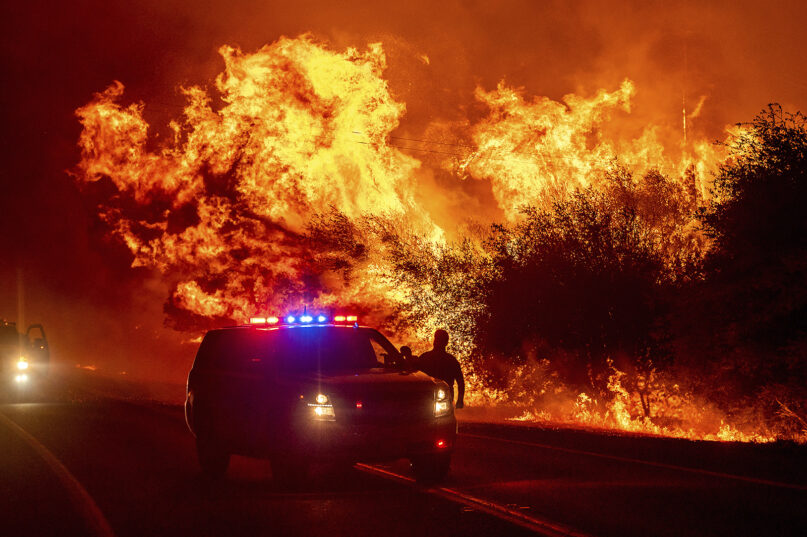 Flames lick above emergency vehicles on Highway 162 as the Bear Fire burns in Oroville, California, Sept. 9, 2020. (AP Photo/Noah Berger)
