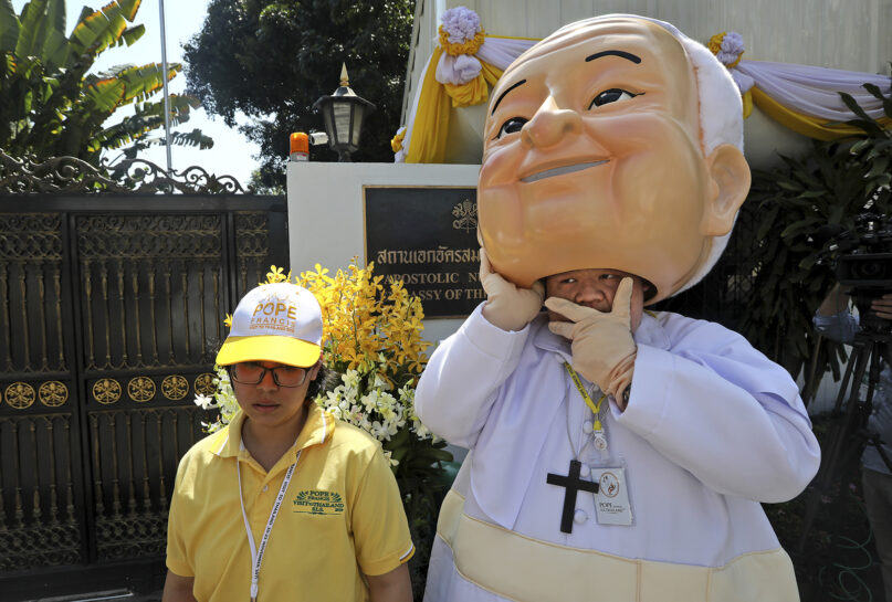 A man lifts a giant mask of Pope Francis off his head as he waits outside the Apostolic Nunciature Embassy of the Holy See in Bangkok on Nov. 20, 2019. Pope Francis toured Thailand and Japan on a trip, part of a mission to boost the morale of those countries’ tiny minority Catholic communities. (AP Photo/Manish Swarup)