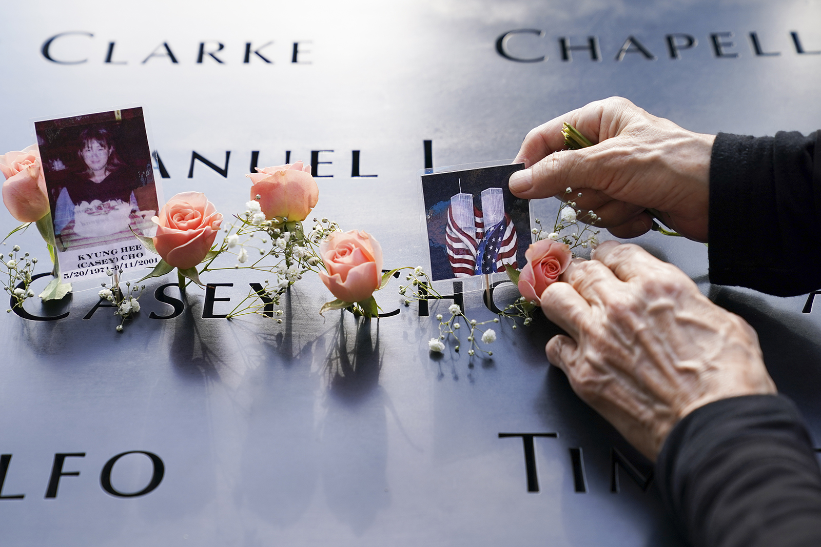Mourners place flowers and pictures in the name cut-out of Kyung Hee (Casey) Cho at the National September 11 Memorial and Museum, Sept. 11, 2020, in New York. (AP Photo/John Minchillo)