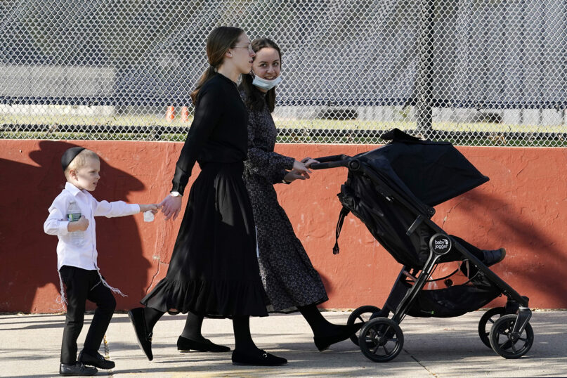 Two young women walk with children during the Jewish holiday of Sukkot on Oct. 4, 2020, in the Borough Park neighborhood of Brooklyn, New York. New York Gov. Andrew Cuomo says he’s ordering schools in certain New York City neighborhoods closed within a day in an attempt to halt a flare-up of the coronavirus. The governor took the action a day after Mayor Bill de Blasio asked the state for permission to reinstate restrictions on businesses and schools in nine ZIP codes in Brooklyn and Queens where the virus was spreading more quickly. (AP Photo/Kathy Willens)