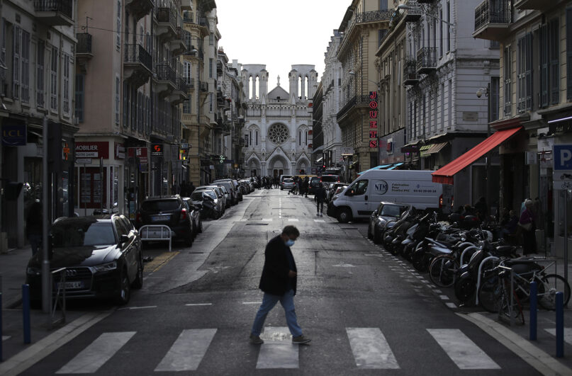 A man crosses the street in front of the Basilica of Notre-Dame in Nice, southern France, after a knife attack took place on Thursday, Oct. 29, 2020. An attacker armed with a knife killed at least three people at a church in the Mediterranean city of Nice, prompting the prime minister to announce that France was raising its security alert status to the highest level. (AP Photo/Daniel Cole)