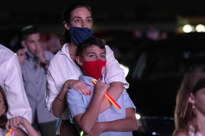 Dana Herseovici stands with her son Tomas during an outdoor Yom Kippur service hosted by the Aventura Turnberry Jewish Center, during the coronavirus pandemic, Sept. 28, 2020, at the Dezerland Park drive-in theatre in North Miami, Florida. (AP Photo/Lynne Sladky)