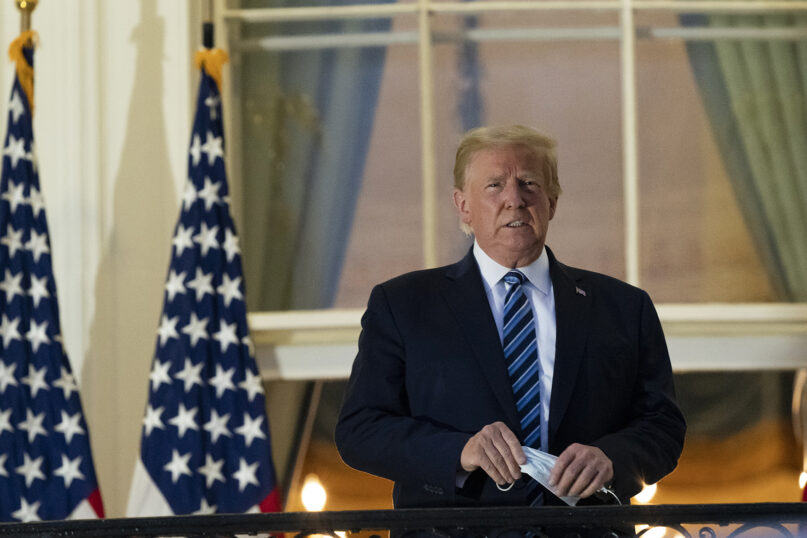 President Donald Trump removes his mask as he stands on the Blue Room Balcony upon returning to the White House on Oct. 5, 2020, in Washington, after leaving Walter Reed National Military Medical Center in Bethesda, Maryland. Trump announced he tested positive for COVID-19 on Oct. 2. (AP Photo/Alex Brandon)