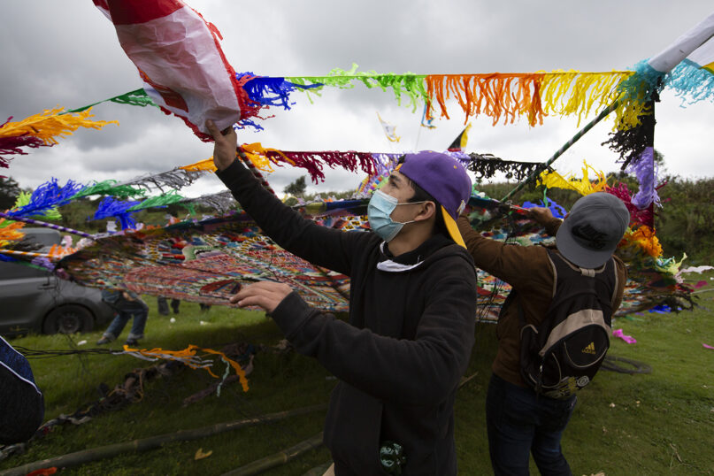 A man helps lift a big kite to be displayed on All Saints Day as part of Day of the Dead celebrations in Santiago Sacatepequez, Guatemala, Sunday, Nov. 1, 2020. According to tradition the kites help keep bad spirits away as the souls of the dearly departed return overnight. (AP Photo/Moises Castillo)