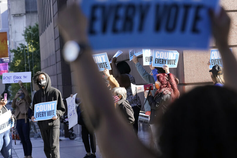 Demonstrators stand across the street from the federal courthouse in Houston, Monday, Nov. 2, 2020, before a hearing in federal court involving drive-thru ballots cast in Harris County. The lawsuit was brought by conservative Texas activists, who have railed against expanded voting access in Harris County, in an effort to invalidate nearly 127,000 votes in Houston because the ballots were cast at drive-thru polling centers established during the pandemic. (AP Photo/David J. Phillip)