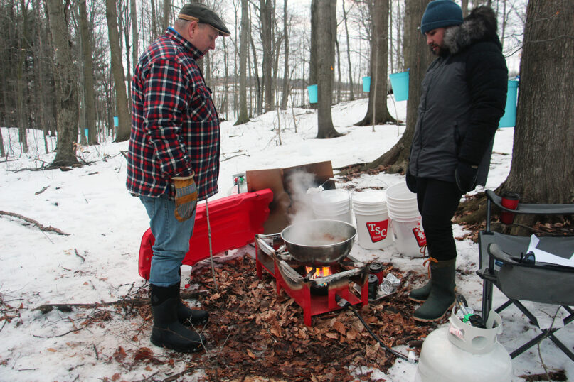 Dave Skene, co-executive director of White Owl Native Ancestry Association, left, and Garrison McCleary, an Indigenous social worker, college professor and land-based educator at White Owl Native Ancestry Association, tend to sap being boiled down into maple syrup on land returned to native peoples in Kitchener, Ontario, on March 4, 2020. RNS photo by Emily McFarlan Miller