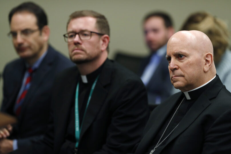 In this Feb. 19, 2019, file photo, from front to back, Samuel Aquila, archbishop of the Denver Diocese of the Roman Catholic Church; the Very Rev. Randy Dollins, vicar general; and Colorado Attorney General Phil Weiser listen about the plan to have a former federal prosecutor review the sexual abuse files of Colorado’s Roman Catholic dioceses at a news conference in Denver. Nine more Catholic priests, including one well known for helping Denver’s homeless, have been identified as sexually abusing children in Colorado in a follow-up report released Dec. 1, 2020, by Weiser. (AP Photo/David Zalubowski, File)