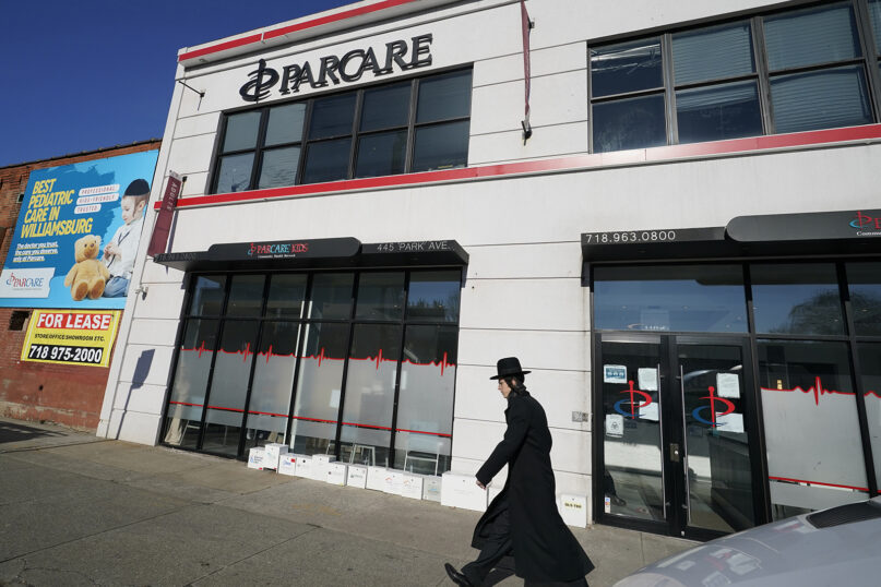 An Orthodox Jewish man walks past the exterior of  a ParCare health care facility, Sunday, Dec. 27, 2020, in the Williamsburg section of Brooklyn in New York. Police and health officials are probing whether the Orange County-based health care provider violated state guidelines in the distribution of COVID-19 vaccines. (AP Photo/Kathy Willens)