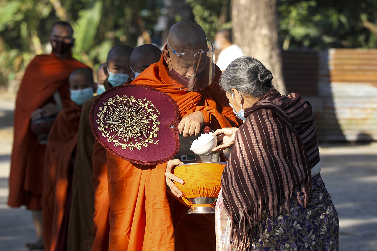 A Buddhist devotee donates alms to a Buddhist monk, Thursday, Dec. 10, 2020, on the outskirts of Yangon, Myanmar. (AP Photo/Thein Zaw)