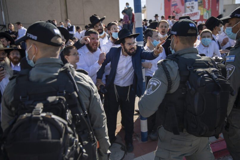 Ultra-Orthodox Jews argue with Israeli border police officers during a protest over the coronavirus lockdown restrictions, in Ashdod, Israel, Sunday, Jan. 24, 2021. As he seeks re-election, Prime Minister Benjamin Netanyahu has turned to a straightforward strategy: Count on the rock-solid support of his ultra-Orthodox political allies and stamp out the coronavirus pandemic with one of the world’s most aggressive vaccination campaigns. But with ultra-Orthodox communities openly flouting safety guidelines and violently clashing with police trying to enforce them, this marriage of convenience is turning into a burden. (AP Photo/Oded Balilty)