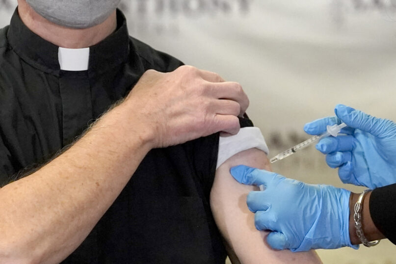 The Rev. Donald Nevins, pastor of St. Agnes of Bohemia Catholic Church in Chicago, left, receives the first of the two Pfizer-BioNTech COVID-19 vaccinations Dec. 23, 2020. (AP Photo/Charles Rex Arbogast)