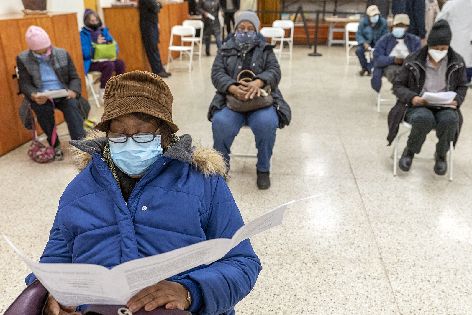 Elaine Chambers reads a coronavirus vaccination pamphlet while resting after receiving the first dose of the vaccine at a pop-up COVID-19 vaccination site at St. Luke's Episcopal Church, Tuesday, Jan. 26, 2021, in the Bronx borough of New York. (AP Photo/Mary Altaffer)
