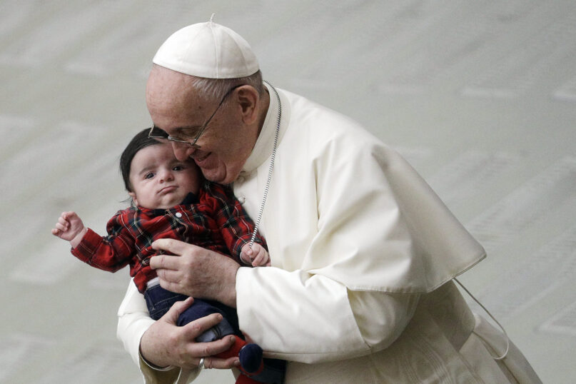 Pope Francis cuddles a baby as he exchanges greetings with Vatican employees in the Paul VI hall , Monday, Dec. 21, 2020, at the Vatican. (AP Photo/Gregorio Borgia)