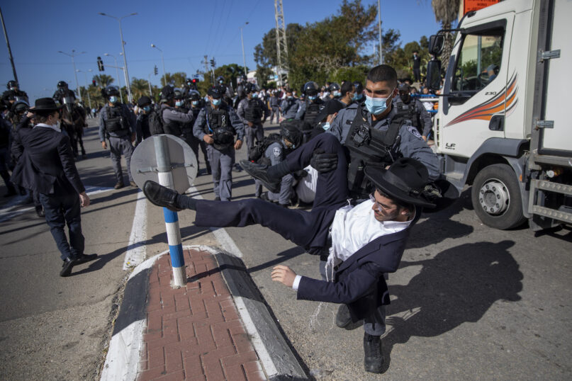 File - In this Sunday, Jan. 24, 2021 file photo, Israeli police officers clash with ultra-Orthodox Jews in Ashdod, Israel,. Ultra-Orthodox demonstrators clashed with Israeli police officers dispatched to close schools in Jerusalem and Ashdod that had opened in violation of coronavirus lockdown rules, on Sunday. (AP Photo/Oded Balilty, File)