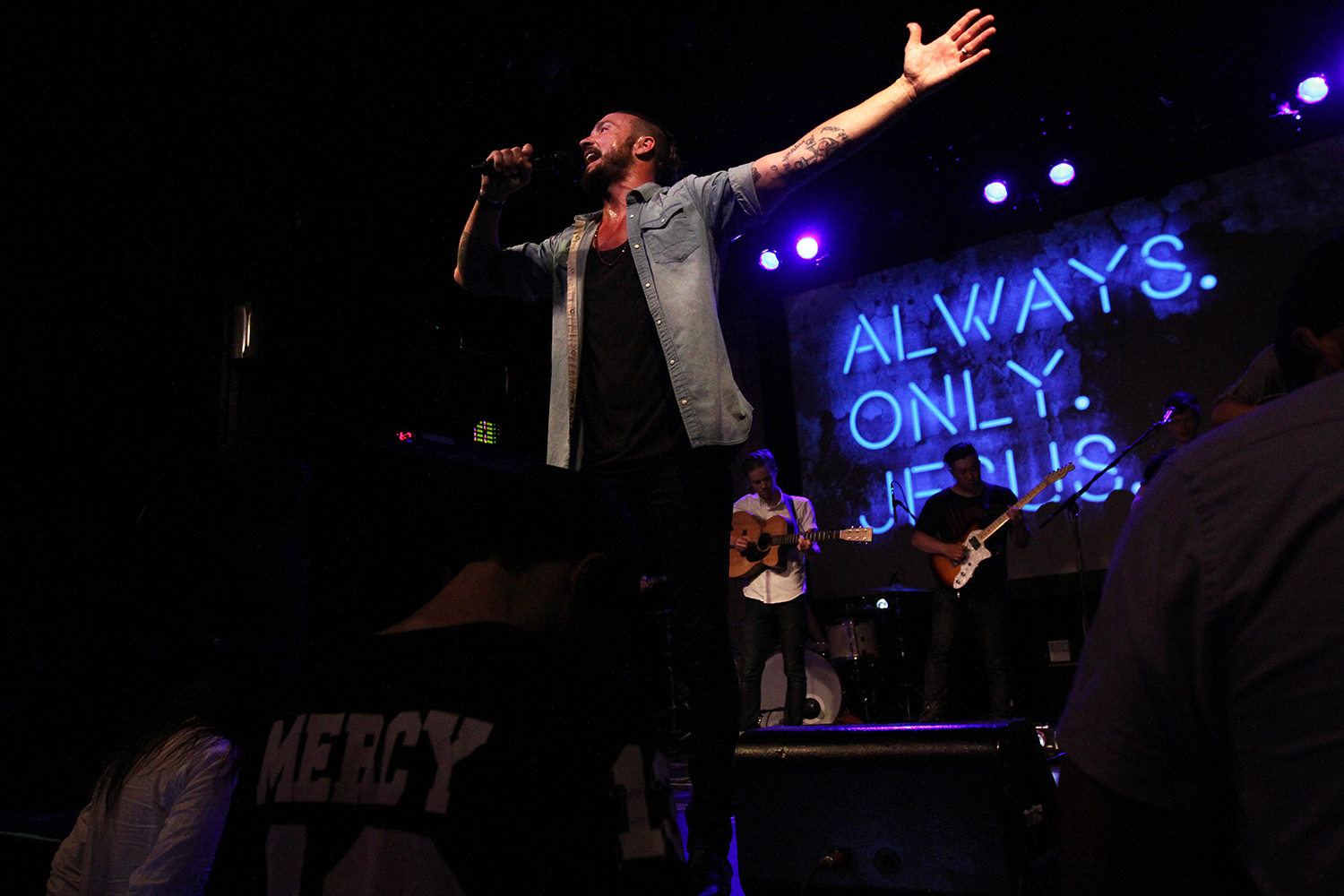 In this July 14, 2013 photo, then-pastor Carl Lentz leads a Hillsong NYC Church service at Irving Plaza in New York. With his half-shaved head, jeans and tattoos, Lentz doesn't look like the typical religious leader. But with its concert-like atmosphere and appeal to a younger demographic, his congregation, Hillsong NYC, is one of the fastest-growing evangelical churches in the city. (AP Photo/Tina Fineberg)