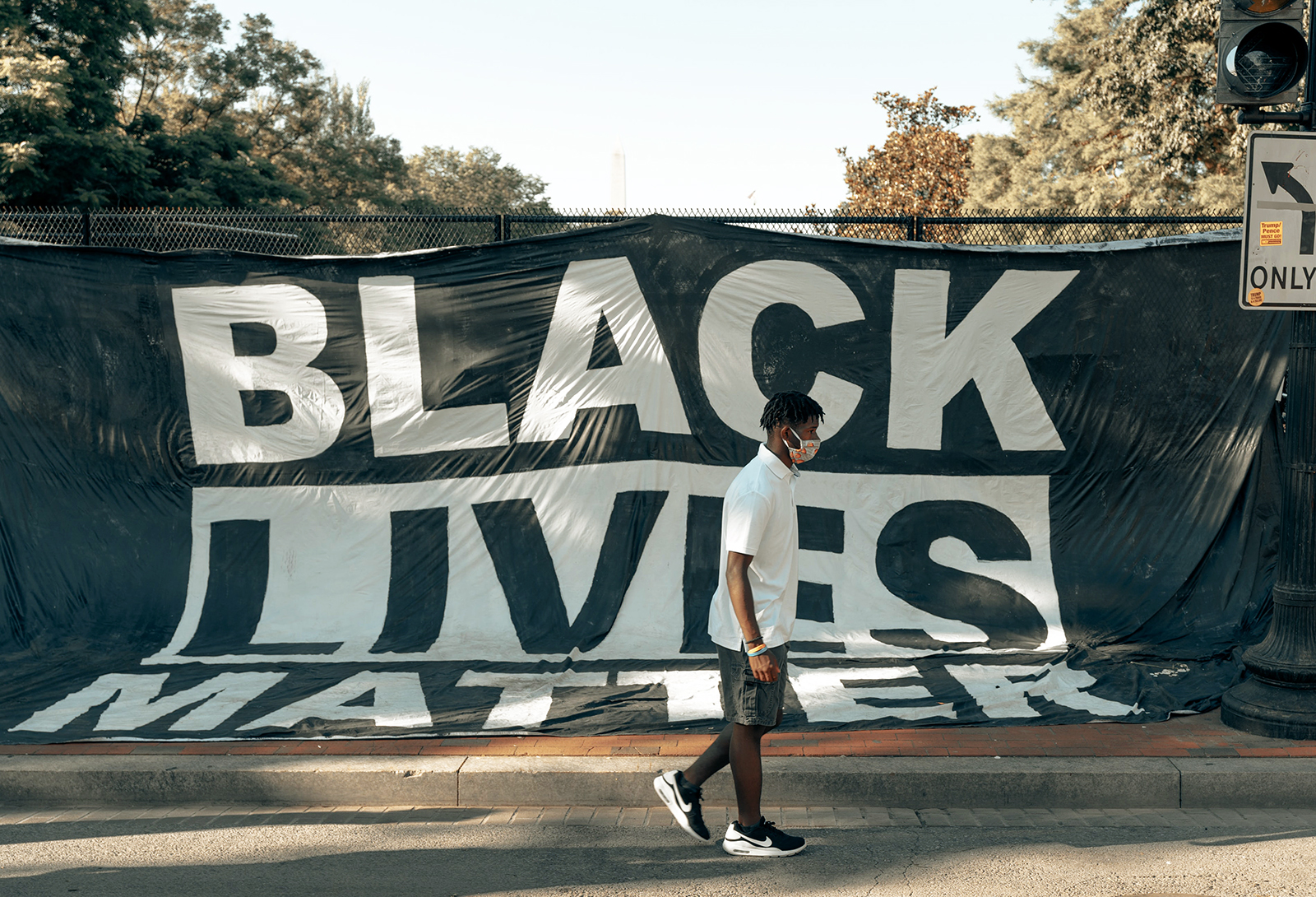 An individual passes a Black Lives Matter sign in Washington, D.C. Photo by Clay Banks/Unsplash/Creative Commons