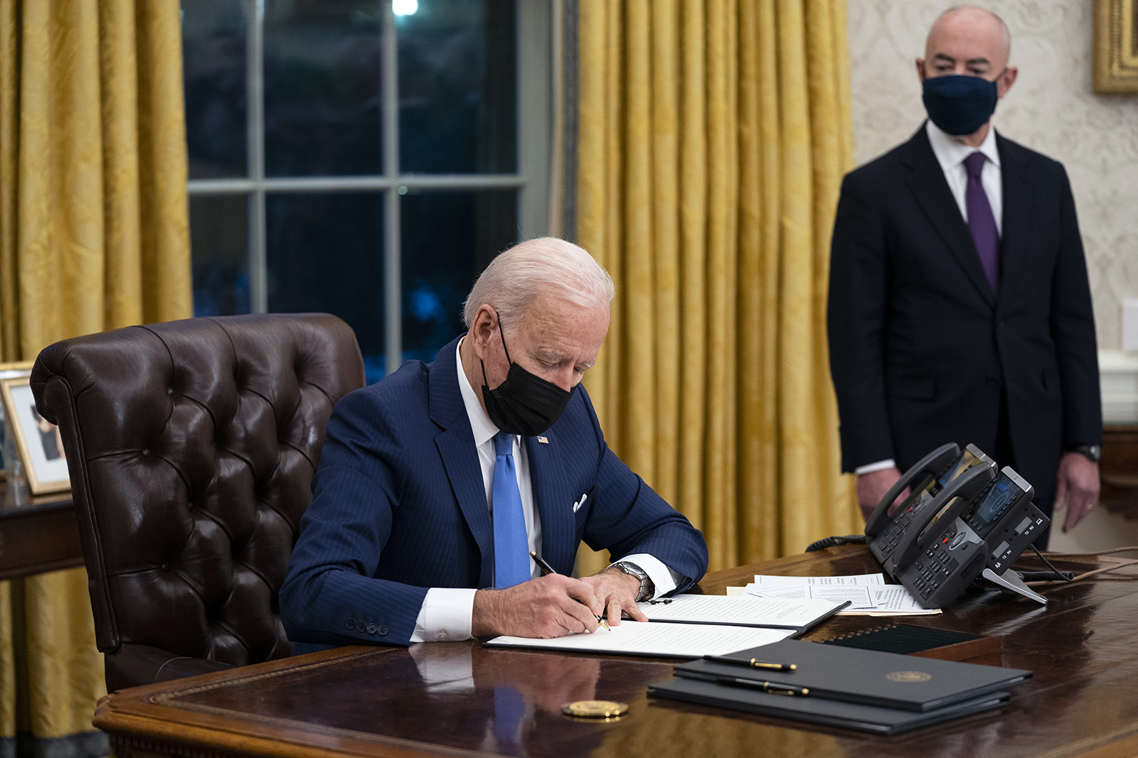 Secretary of Homeland Security Alejandro Mayorkas looks on as President Joe Biden signs an executive order on immigration, in the Oval Office of the White House, Tuesday, Feb. 2, 2021, in Washington. (AP Photo/Evan Vucci)